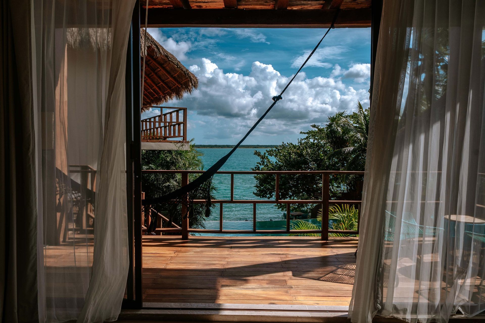 Una terraza de madera con una hamaca y sillas.