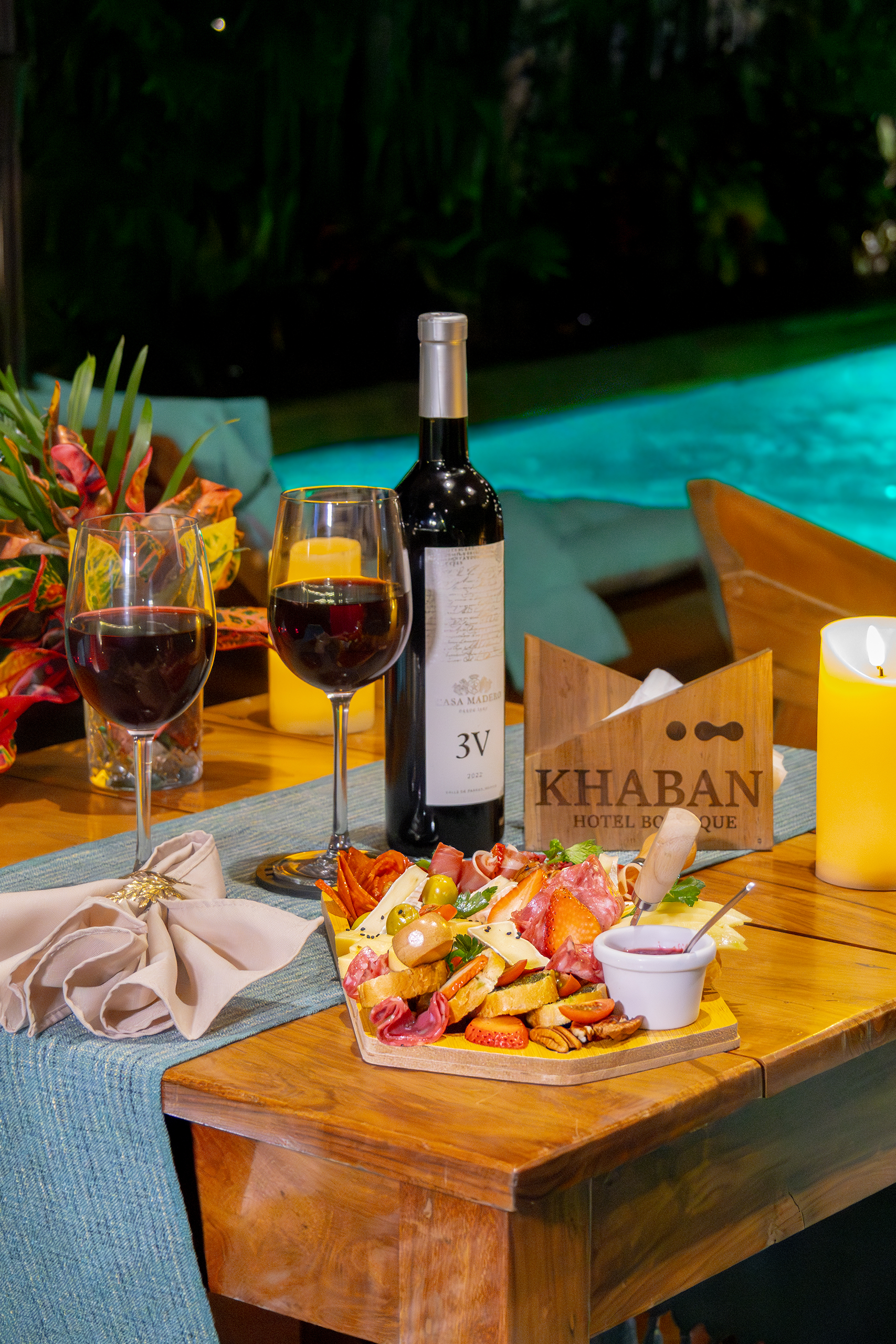 Cena romántica en el restaurante Kinal de Khaban Bacalar con tabla de quesos, vino tinto y vista a la alberca principal rodeada de naturaleza.