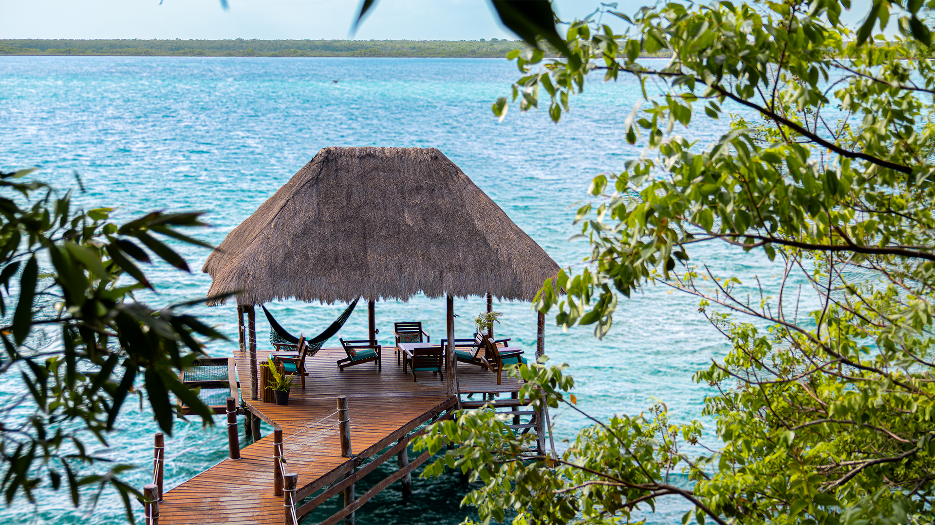 Muelle de Khaban Bacalar con palapa, hamacas y sillas sobre la Laguna de Bacalar.