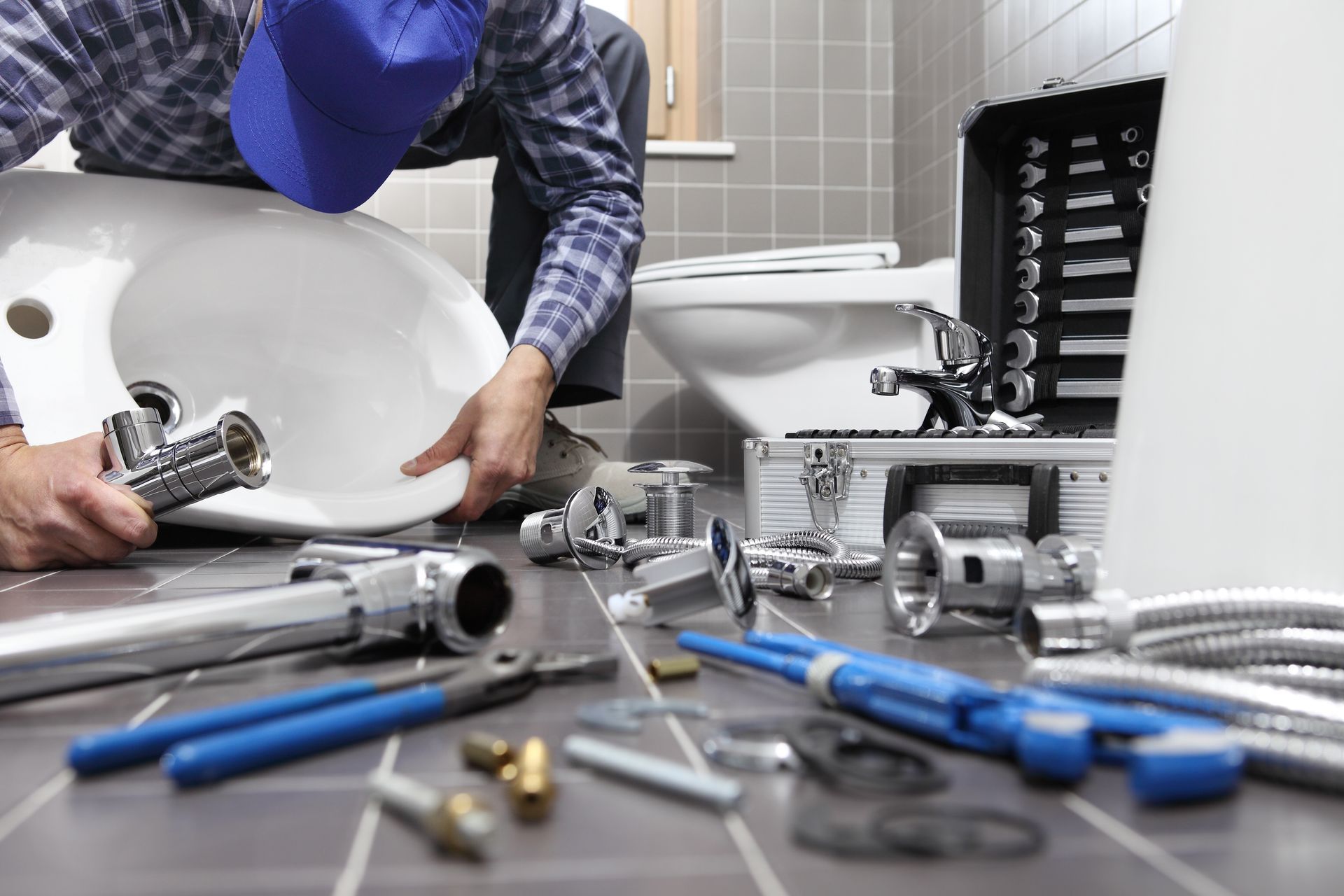 A plumber is fixing a sink in a bathroom.