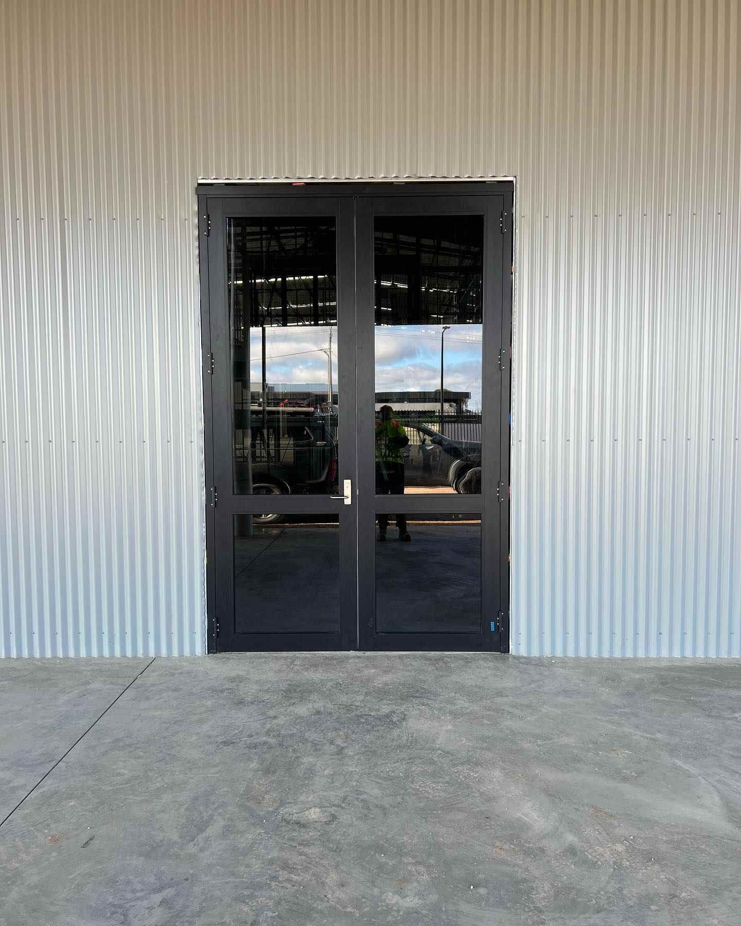 A Black Door Positioned In Front Of A Metal Wall — SG Glass & Aluminium in Wagga Wagga, NSW