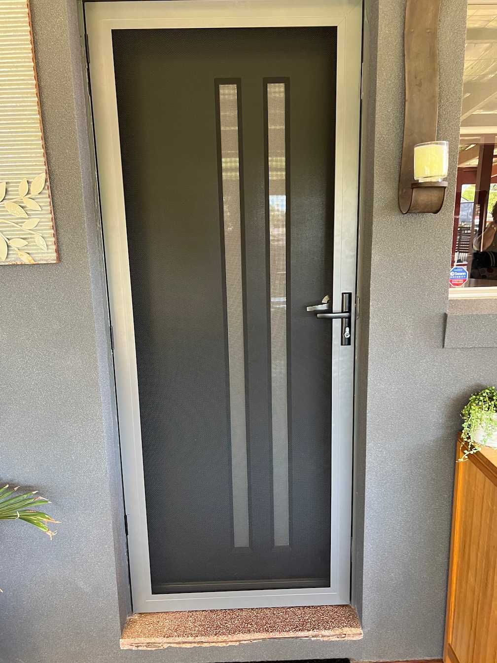 A Black Door With A White Frame Mounted On A Gray Wall — SG Glass & Aluminium in Wagga Wagga, NSW