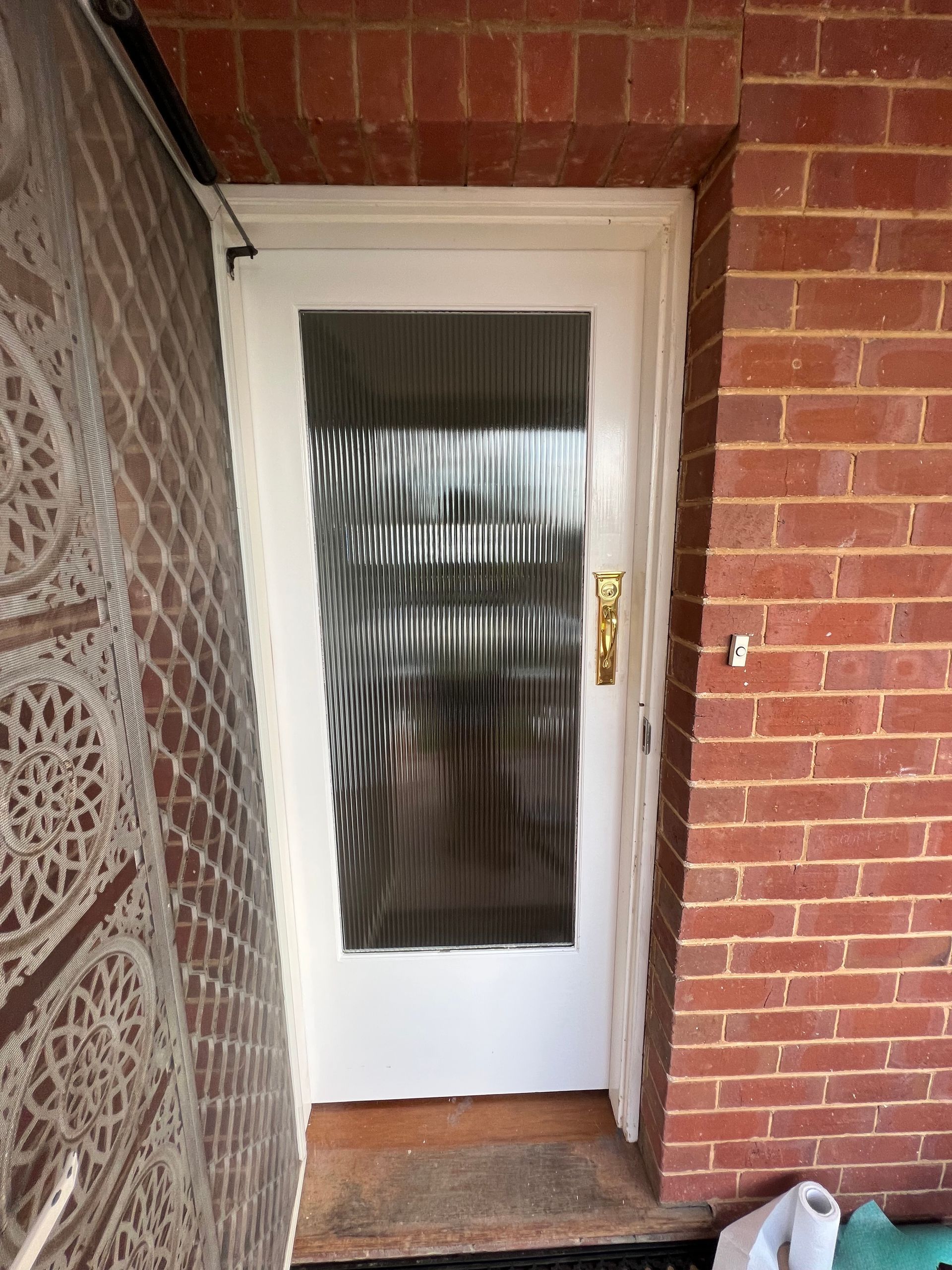 A Brick Wall Featuring A White Door With A Broom Leaning Against It — SG Glass & Aluminium in Wagga Wagga, NSW