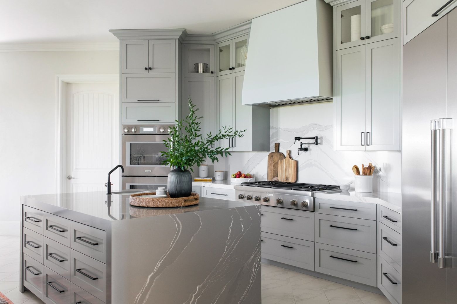 Bright modern kitchen with gray cabinets, marble island, and stainless steel appliances