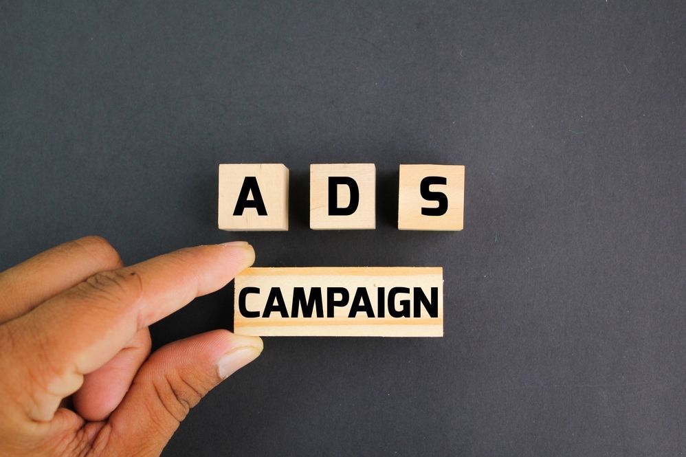 Una mano sostiene un bloque de madera con las palabras campaña publicitaria escritas en él.