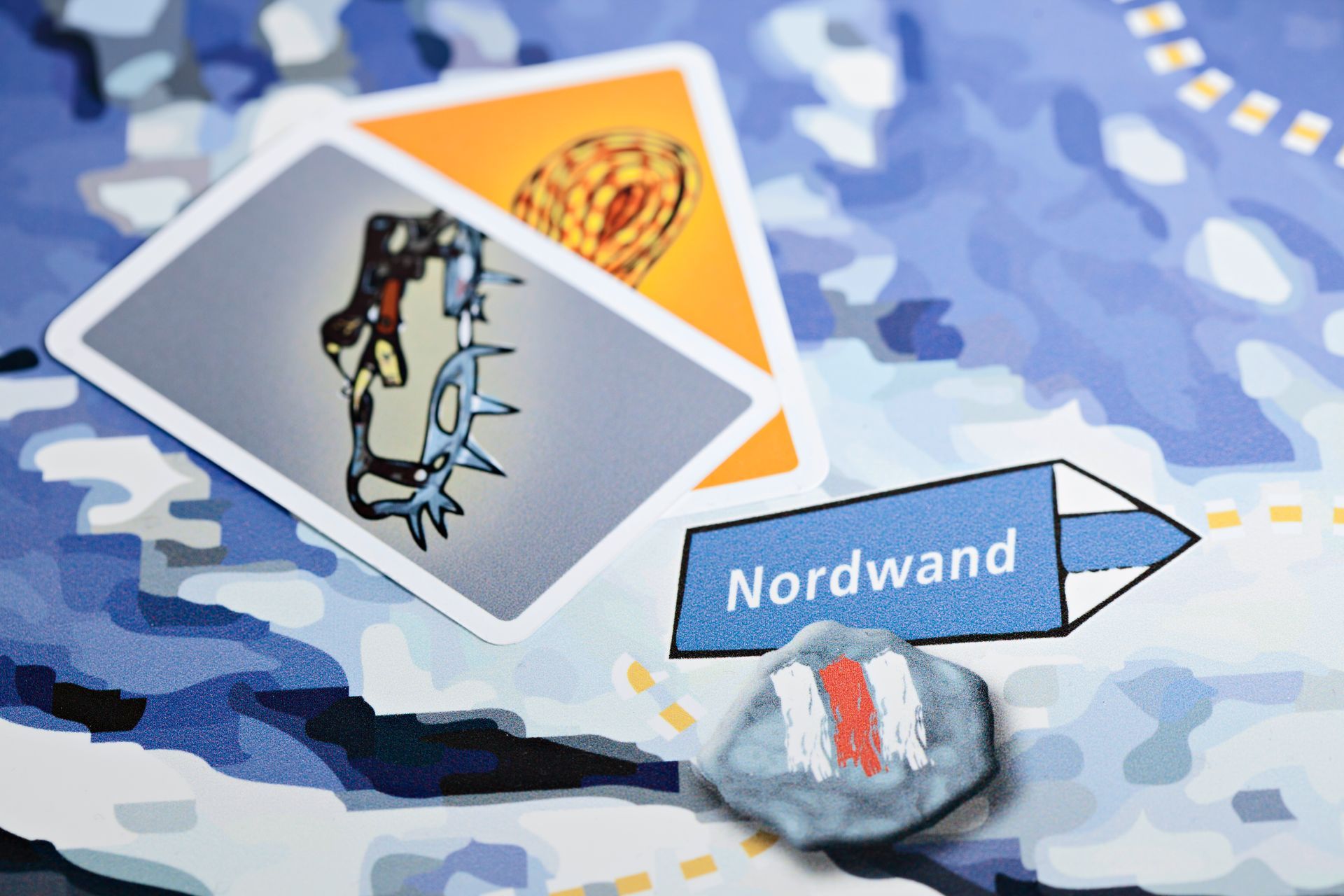 游戏板、卡片、一块涂有条纹的石头和一个标有“Nordwand”的标志。