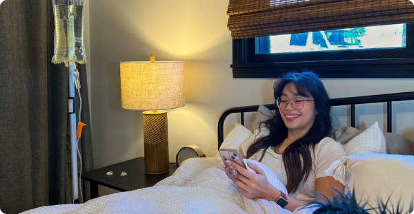 A woman is laying in bed looking at her phone.