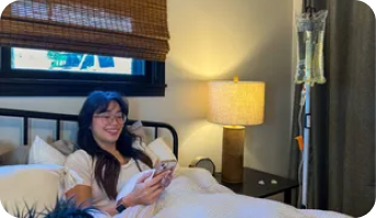 A woman is laying in bed looking at her phone.
