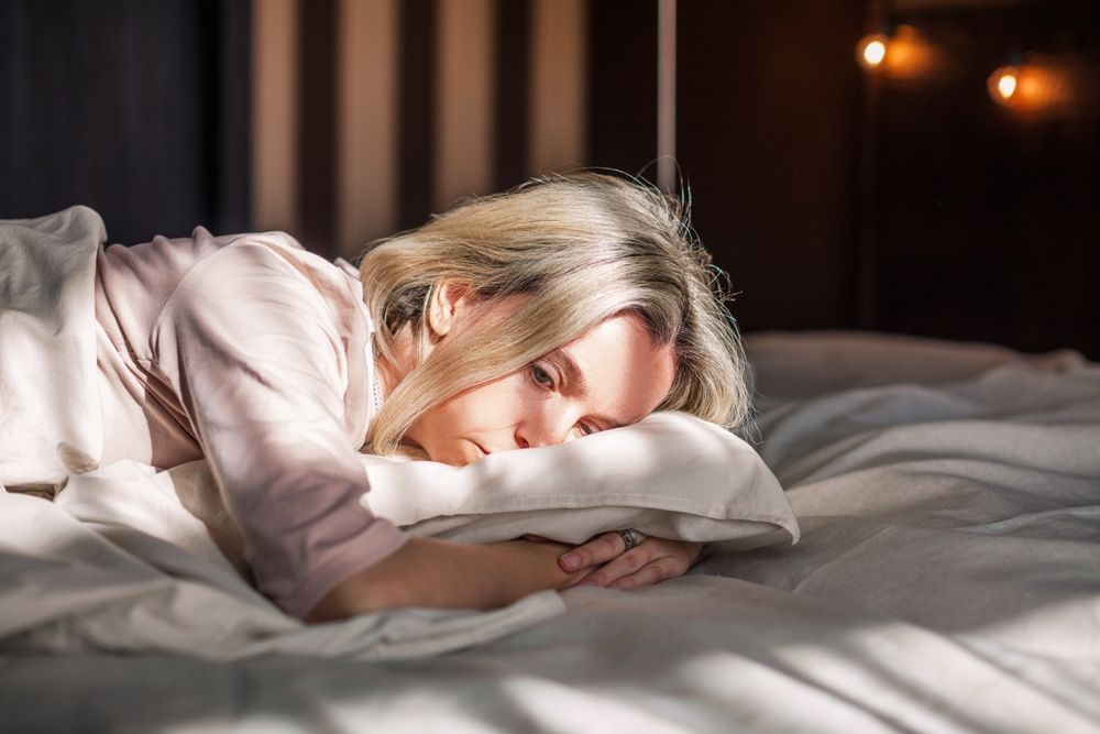 A woman is sleeping on a bed with her head on a pillow.