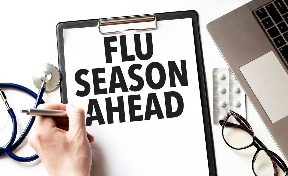 A person is writing on a clipboard that says `` flu season ahead ''.