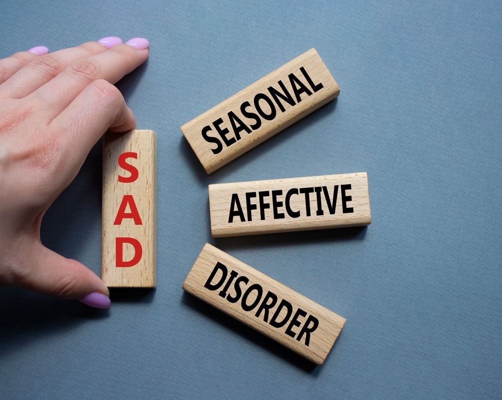 A person is holding a wooden block with the word sad written on it.