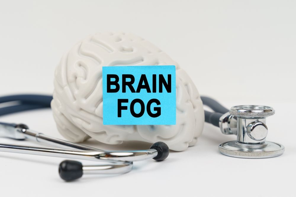 A stethoscope and a brain with a sticky note that says brain fog