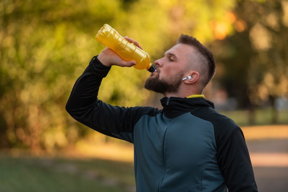 A man is drinking a bottle of orange juice.