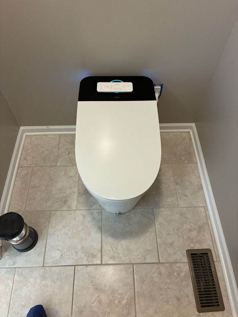 Bright bathroom with a white toilet, beige walls, and carpeted floor near a doorway.