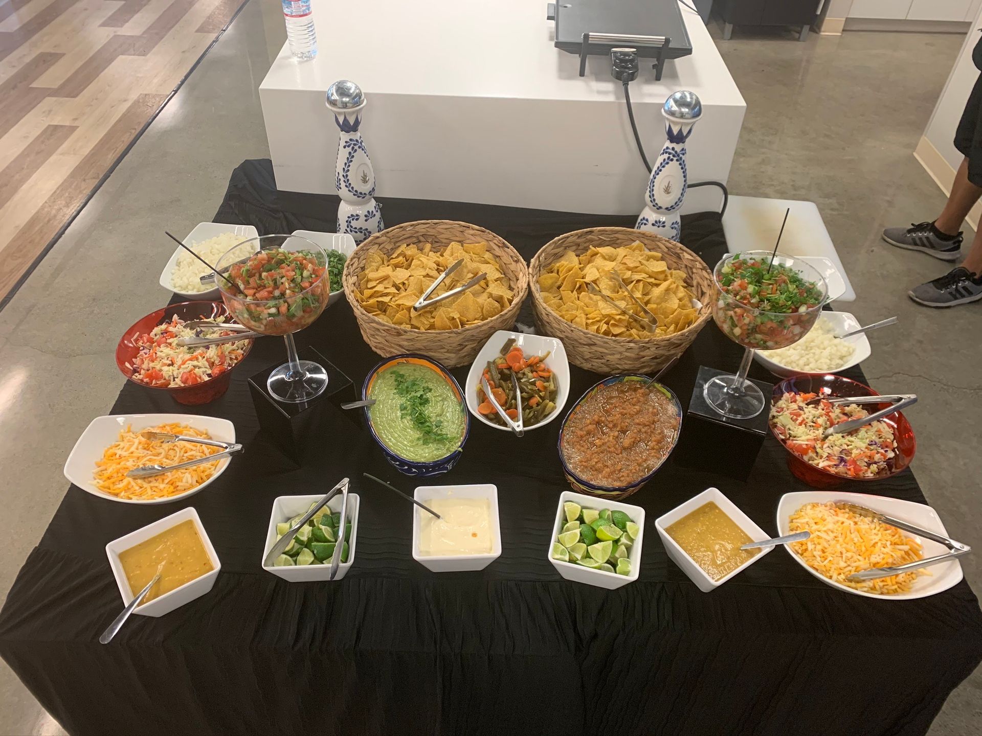 A table with a buffet of tortilla chips, various toppings, and sauces.