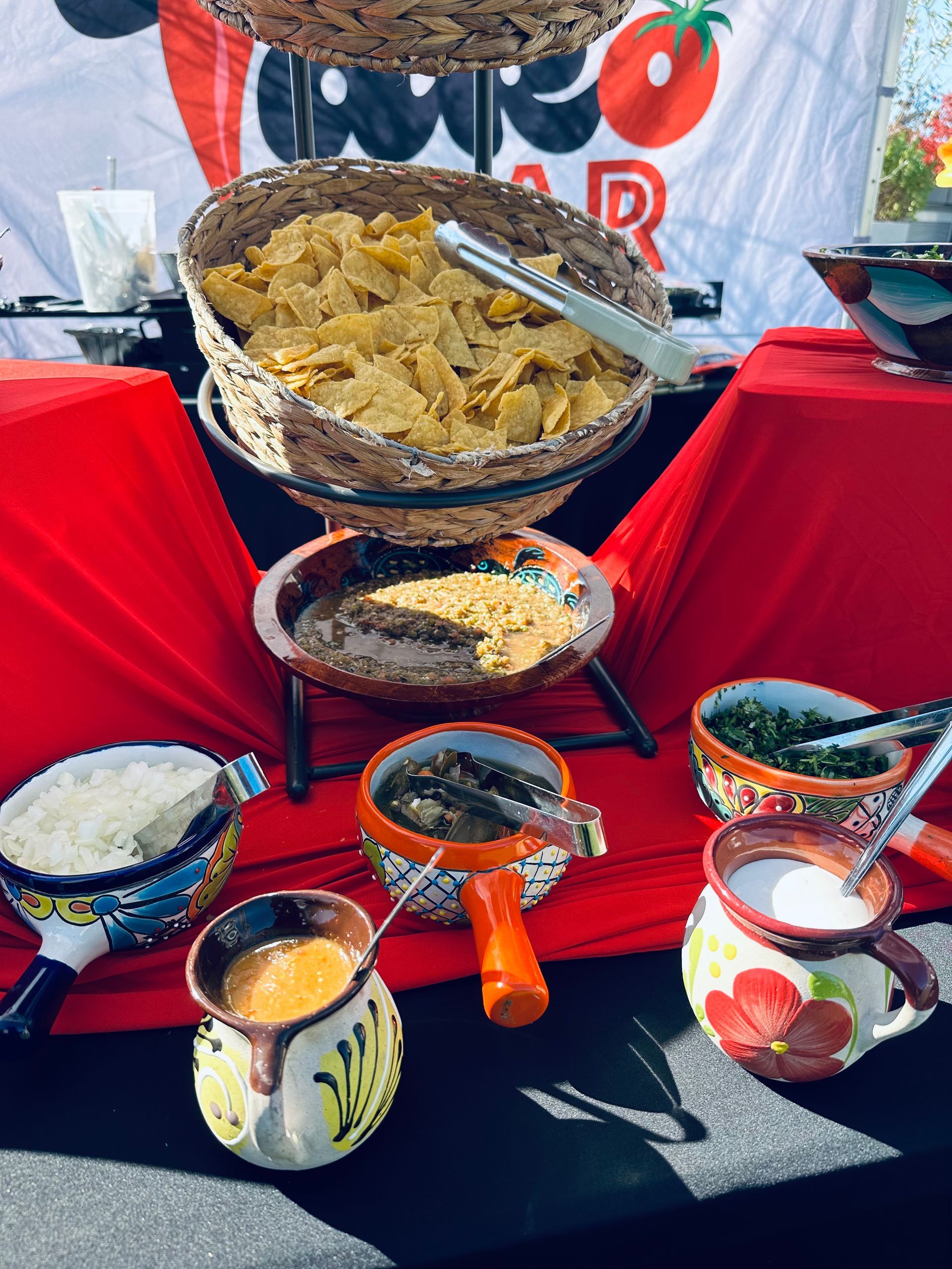 Mexican food bar with chips, salsa, and toppings in colorful ceramic bowls.