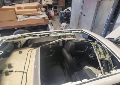 A car with the sunroof removed is sitting in a garage.