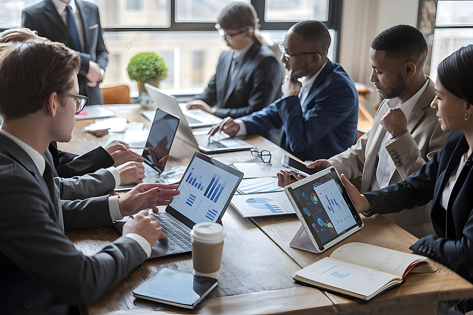 Business meeting around a conference table with laptops, notebooks, and coffee in a bright office