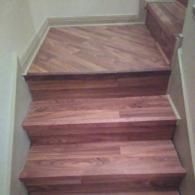 Wooden staircase with a small landing and three visible steps, viewed from indoors.