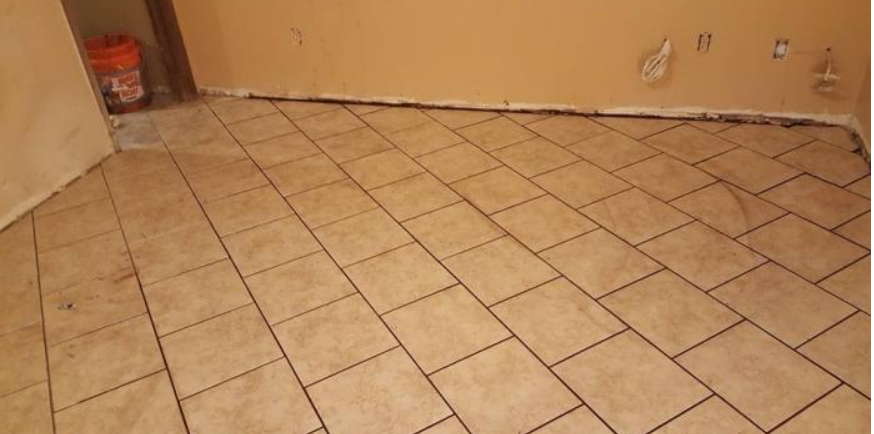 Empty room with beige tiled floor, tan walls, and exposed electrical outlets.