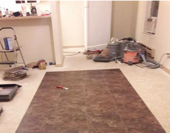 Living room with a large brown rug, scattered tools, and renovation clutter in the background