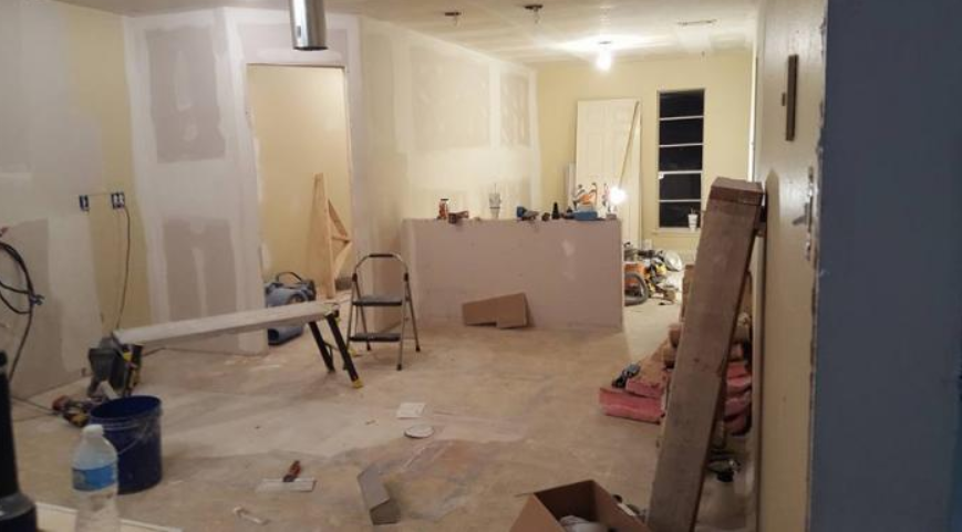 Renovated room with tools, ladders, paint buckets, and drywall in progress
