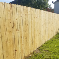 Wooden privacy fence beside a grassy yard on a sunny day