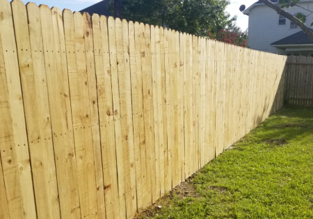 Wooden privacy fence along a grassy yard on a sunny day