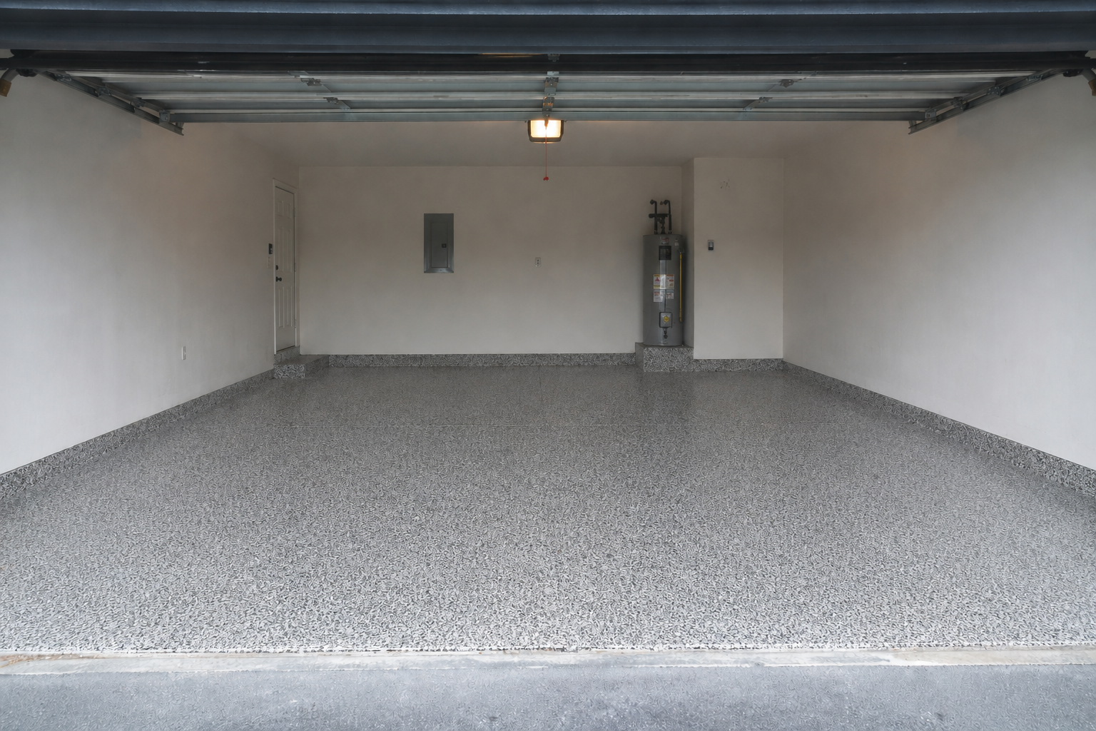 Empty garage with gray gravel floor and a closed overhead door.