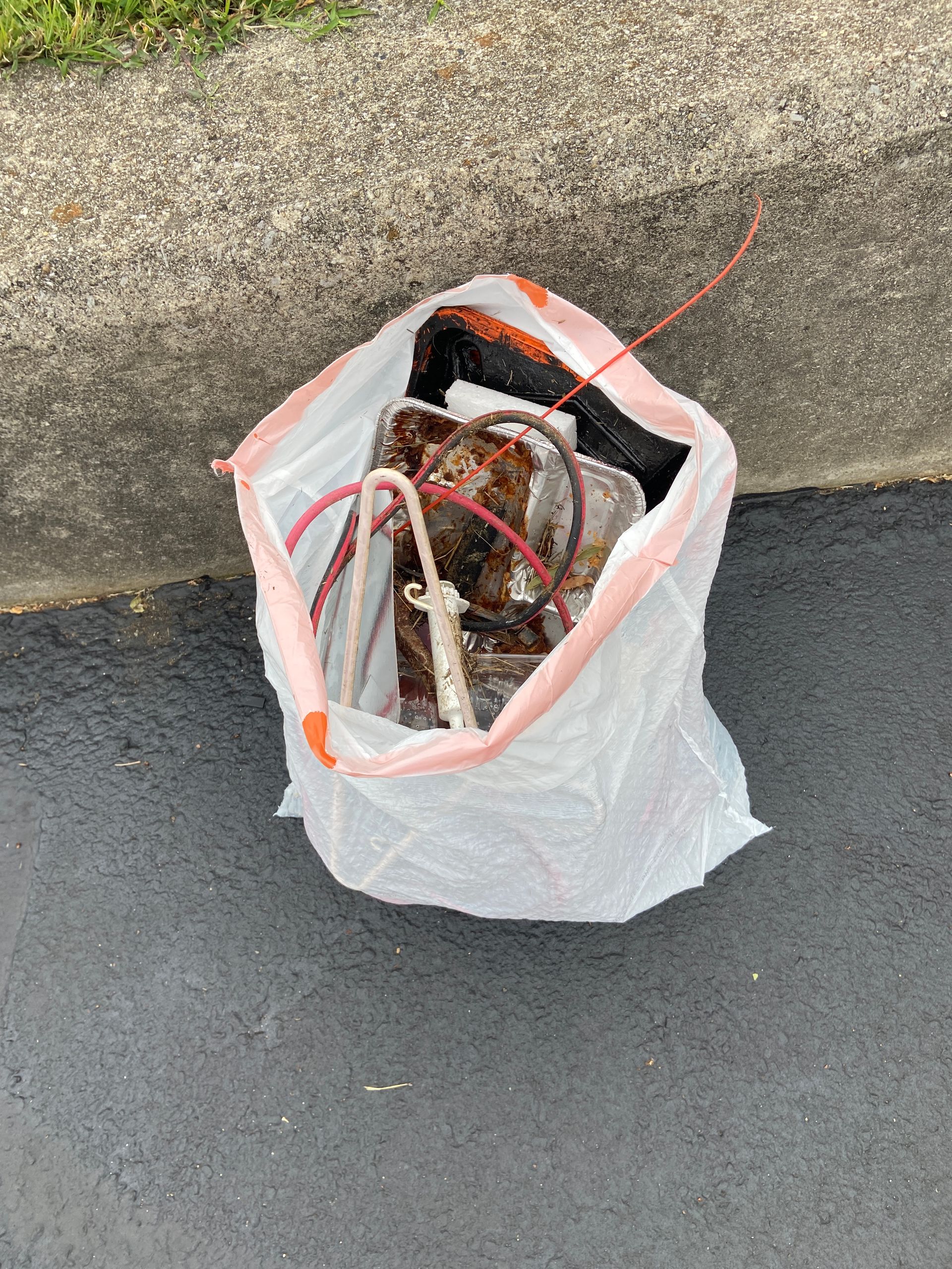 A plastic bag filled with wires is sitting on the ground.