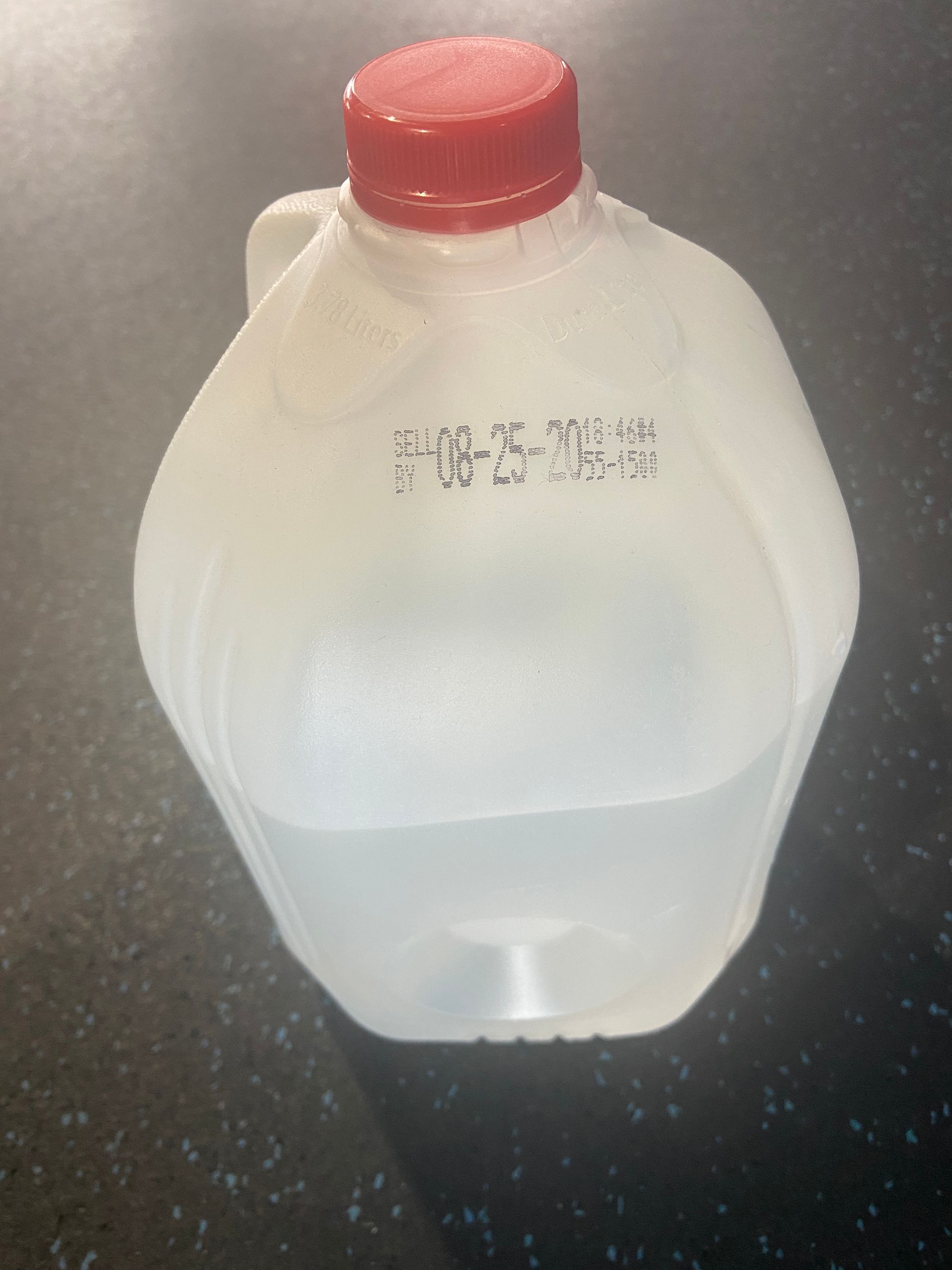 A gallon of water with a red cap has a date stamp on it