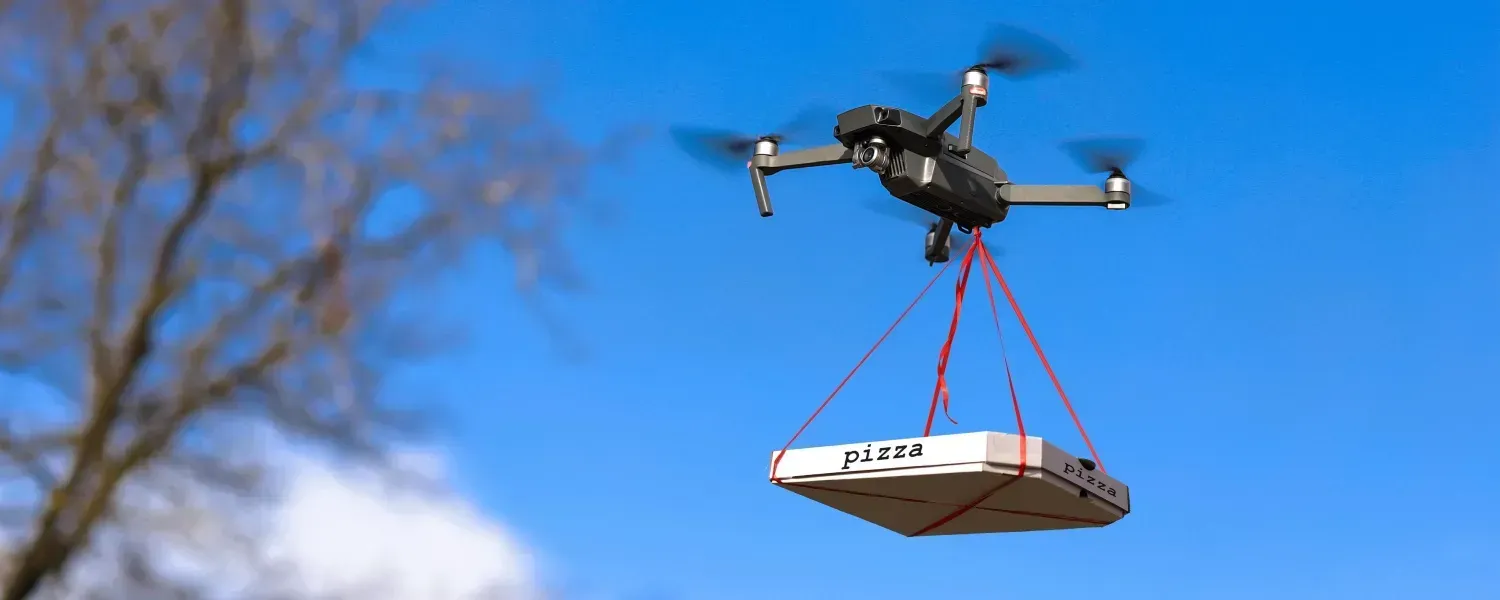 A drone is carrying a pizza box in the air.