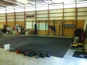A gym with a lot of kettlebells on the floor