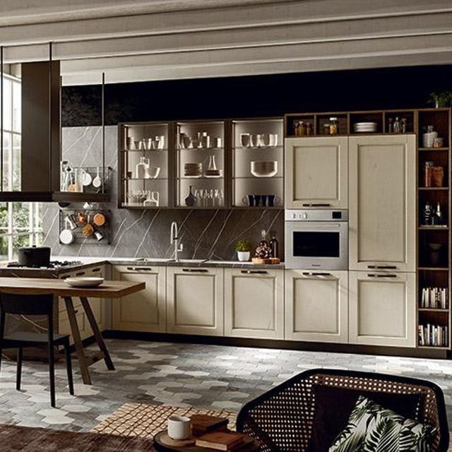 Mobili e ripiani della cucina beige con una parete decorativa nera. Scaffali in legno e pavimento in piastrelle esagonali.