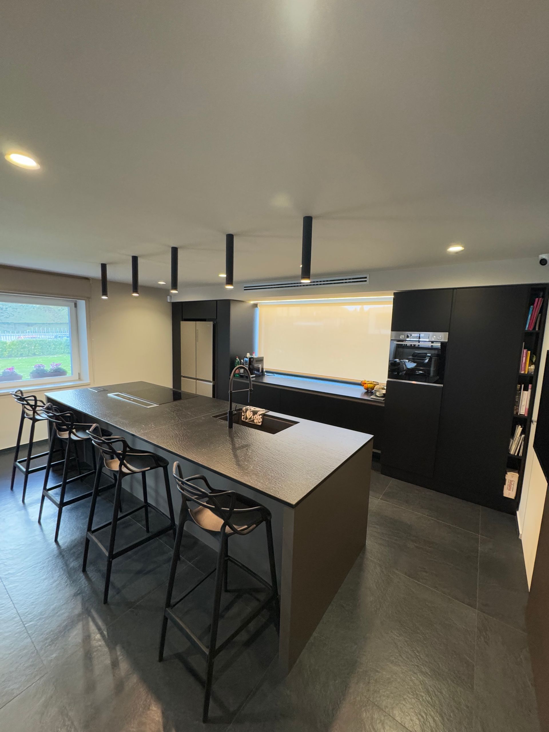 Cucina semi-disegnata con elettrodomestici in acciaio inossidabile, paraschizzi in marmo e mobili grigio scuro.