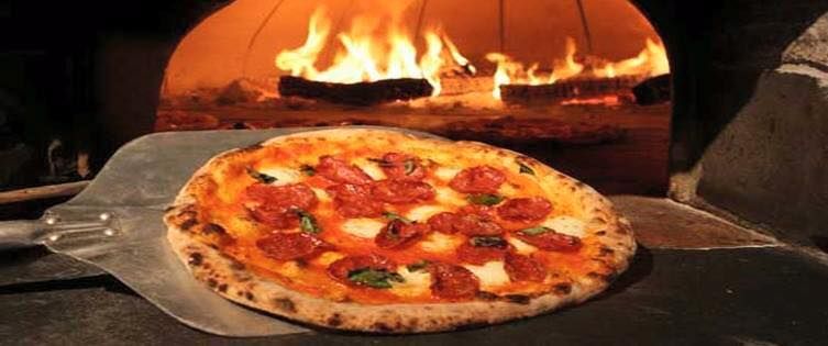 Una pizza è appoggiata su una pala davanti al forno.