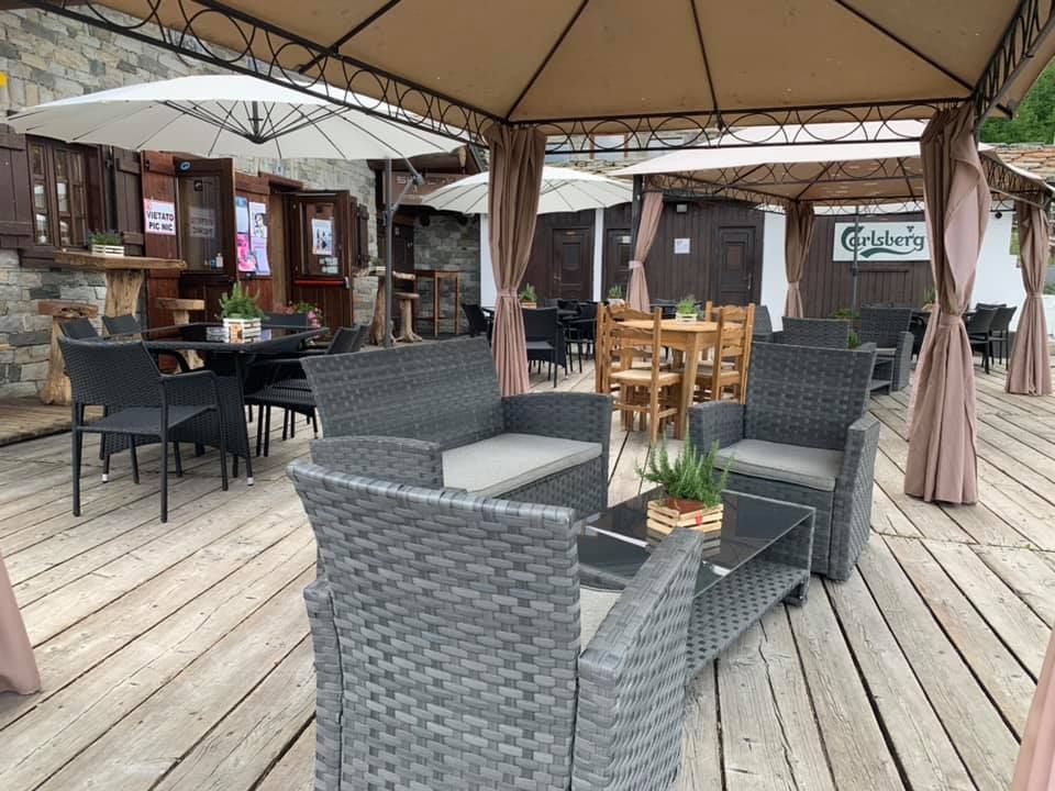 Un ponte di legno con mobili in vimini e tavoli sotto gli ombrelloni.