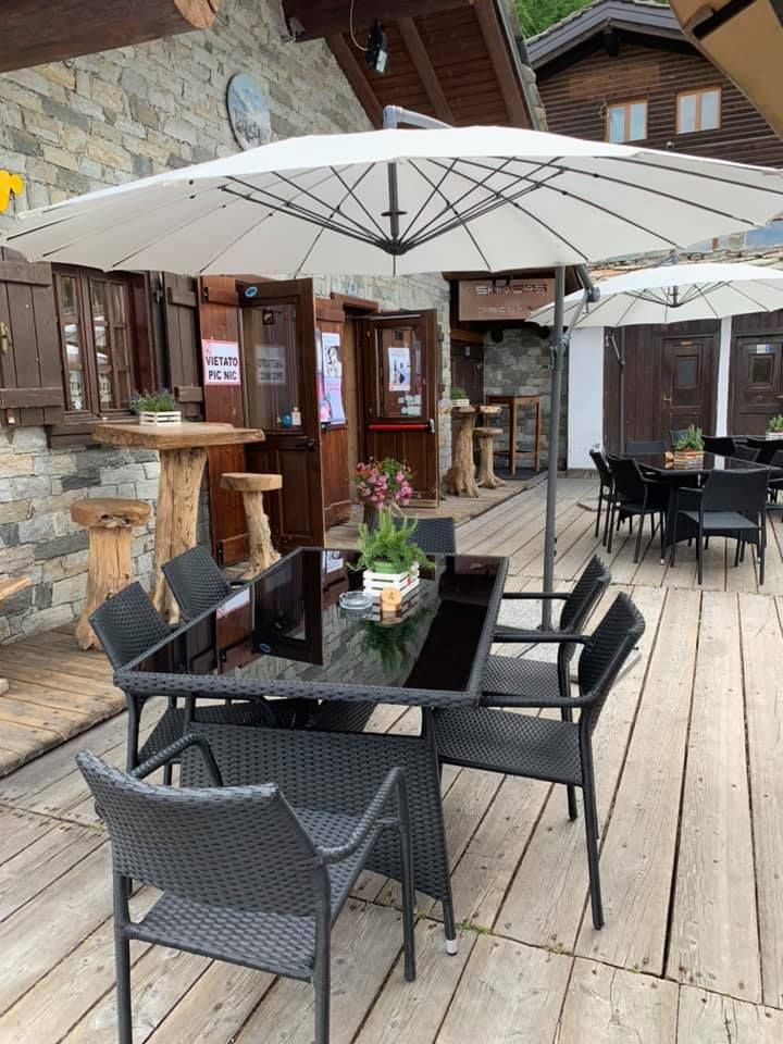 Una terrazza in legno con tavoli e sedie sotto gli ombrelloni.