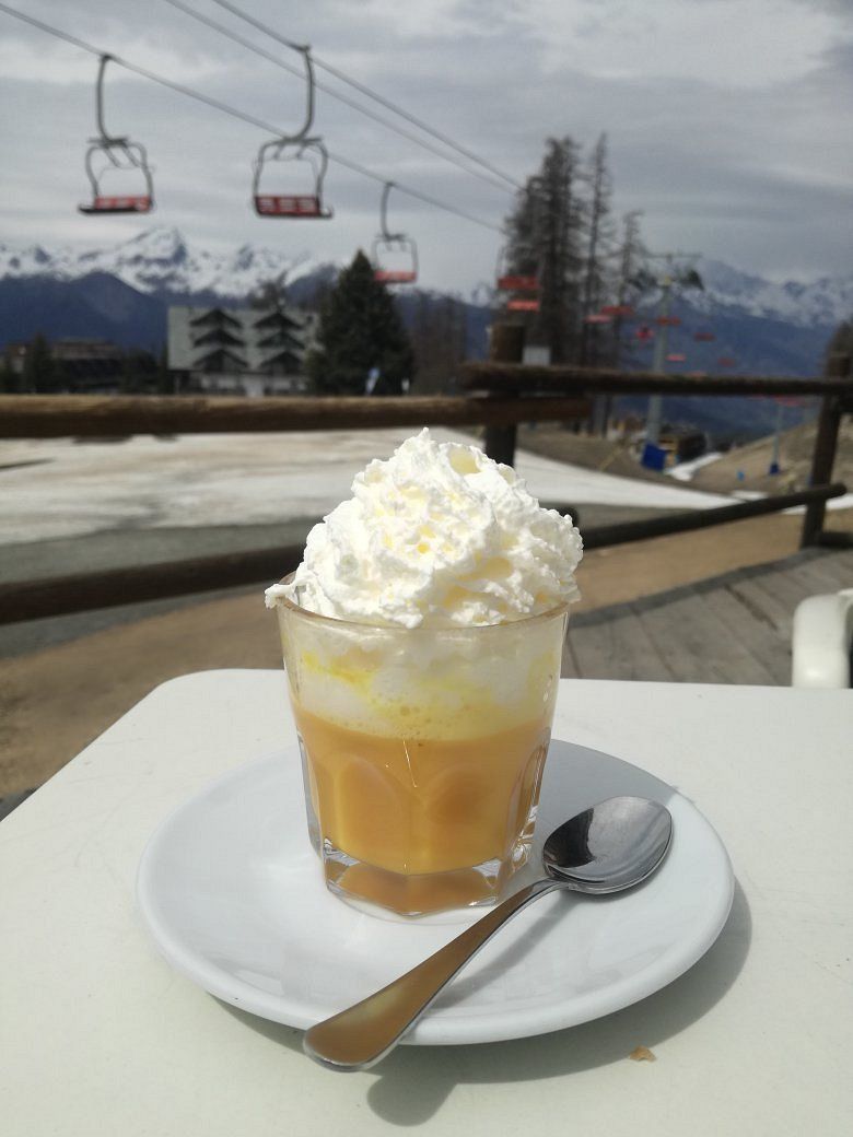 Una tazza di caffè con panna montata e un cucchiaio su un piatto bianco