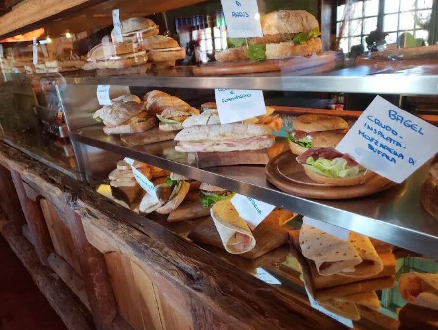 Una vetrina piena di panini e un cartello che dice bagel