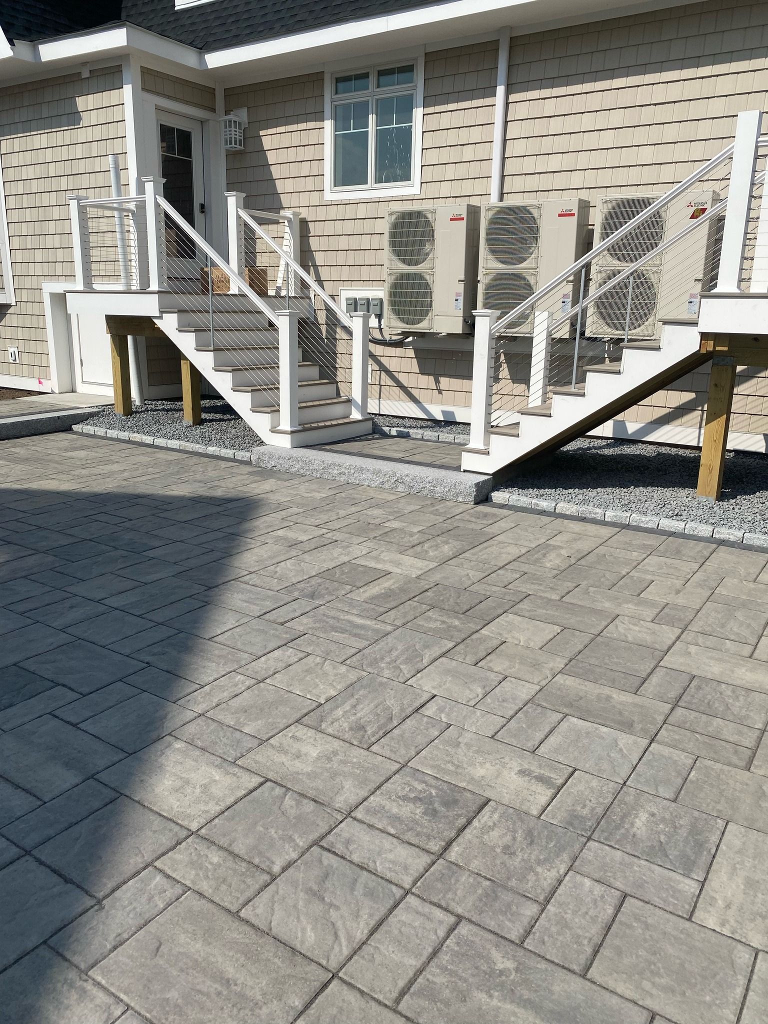 Apartment building entrance with twin staircases, air-conditioning units, and a paved courtyard