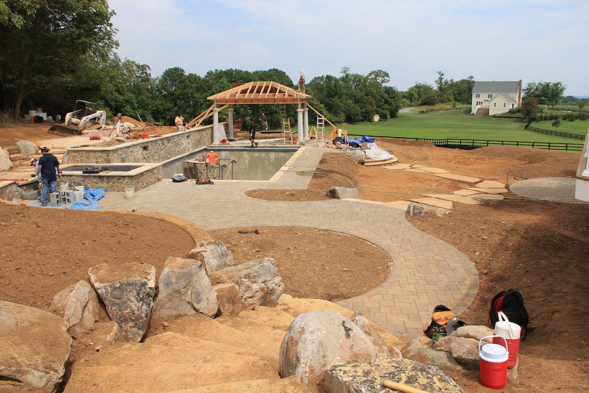 Children playing in a sandy park area with stone features and a small pavilion in the background