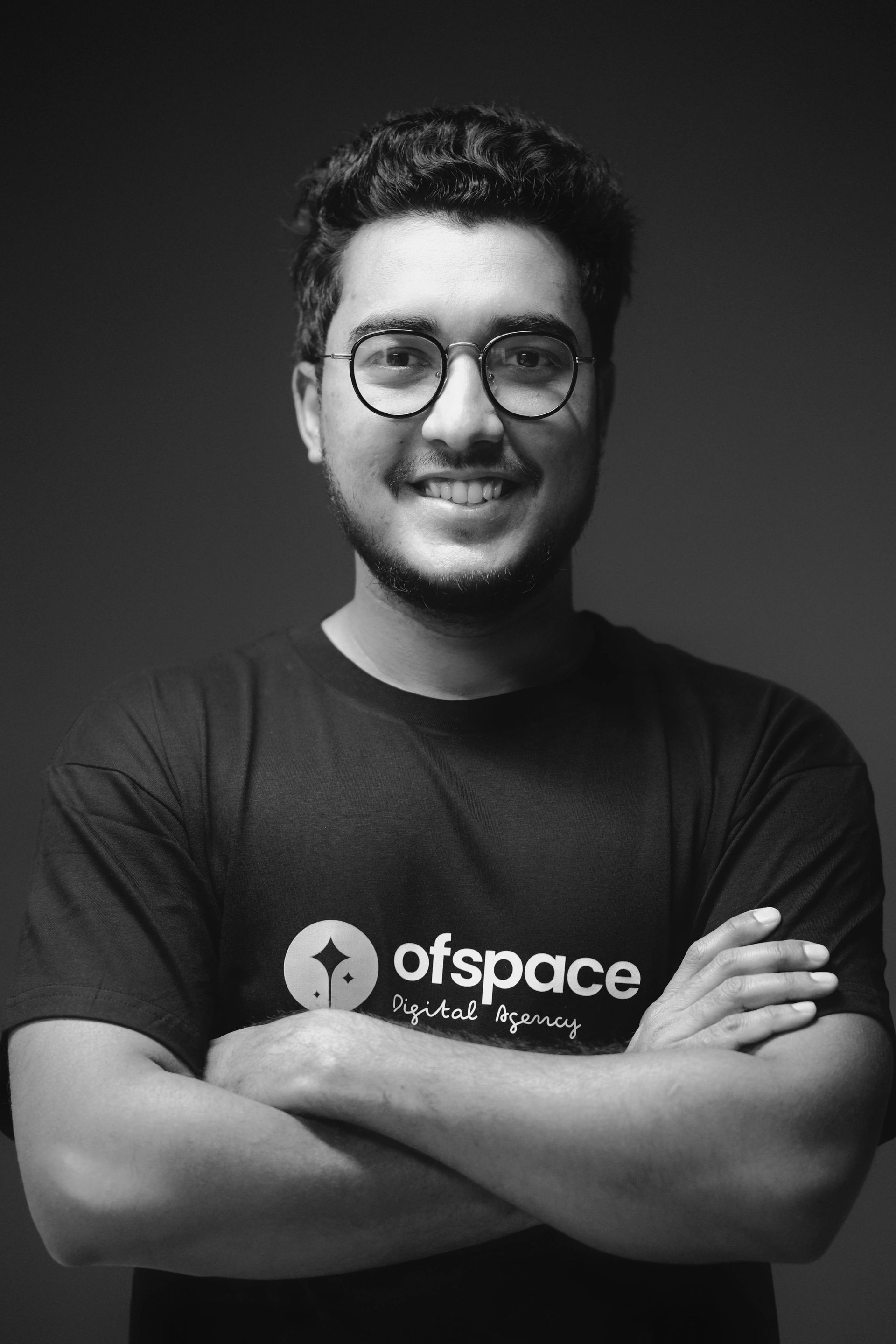 Person with glasses and folded arms wearing a black 