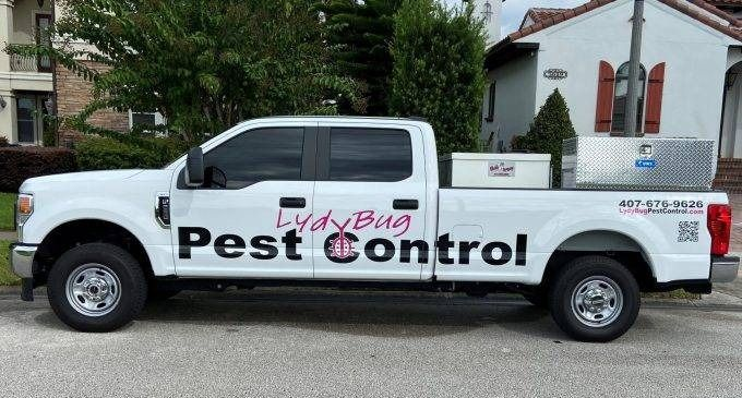 White pest control pickup truck parked on a residential street, with large company logo on the side.