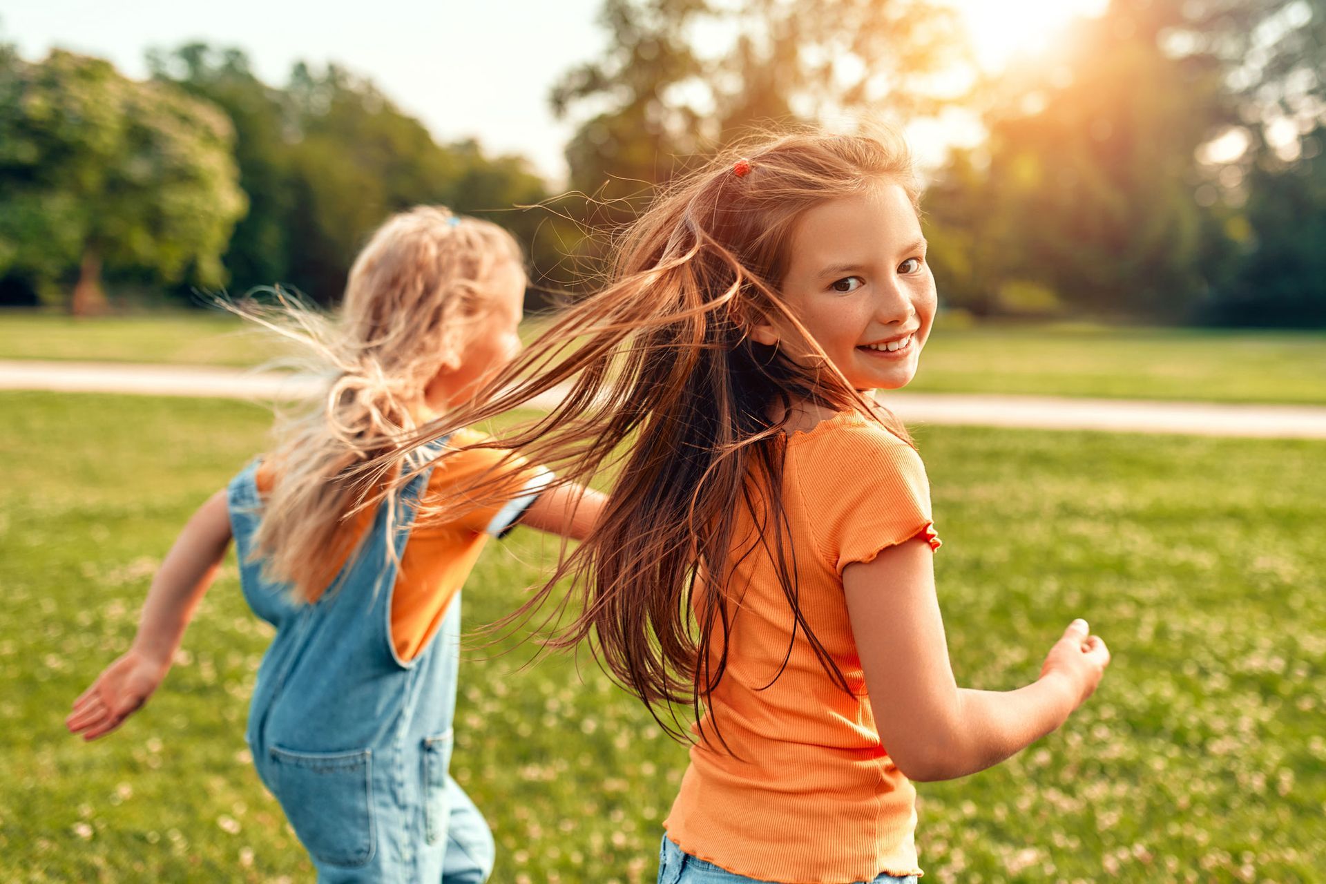 Two little girls are running in a park.