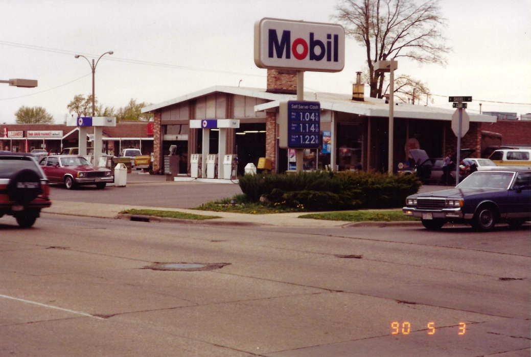 Mobil gas station on a street corner, with gas prices displayed; cars and other businesses are visible.