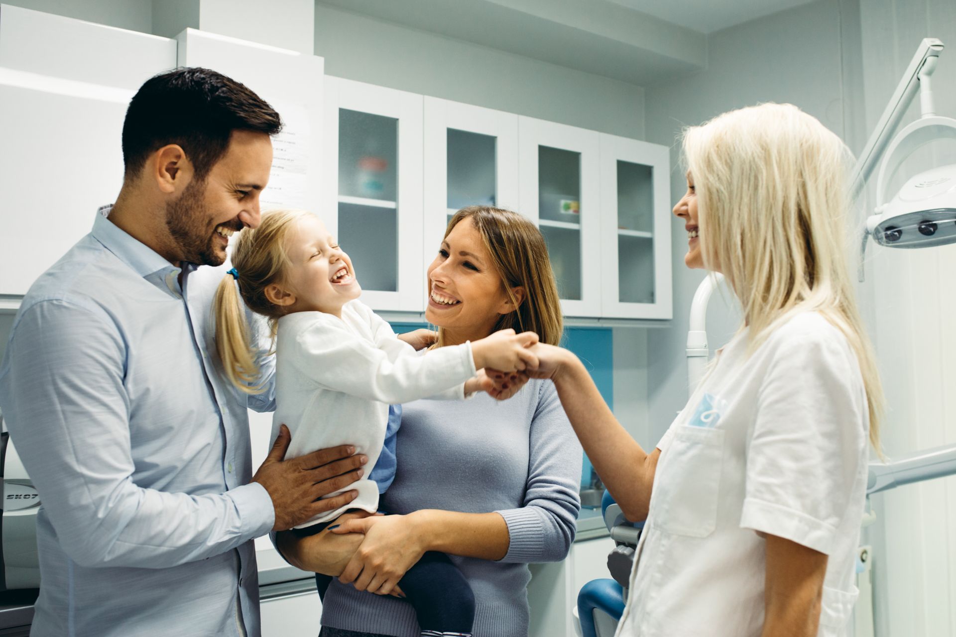 Family smiling with a child in a bright clinic, with a doctor standing nearby