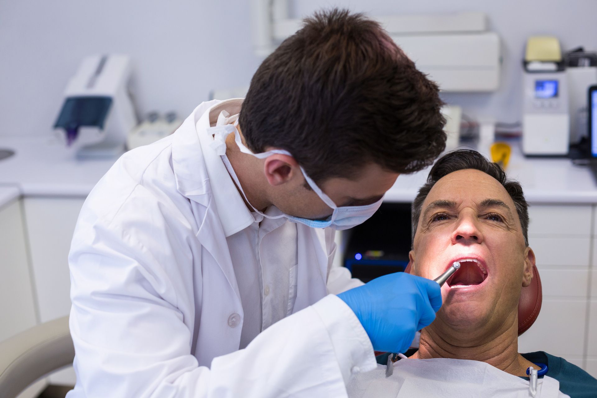 Dentist examining a male patient with tools in the clinic.
