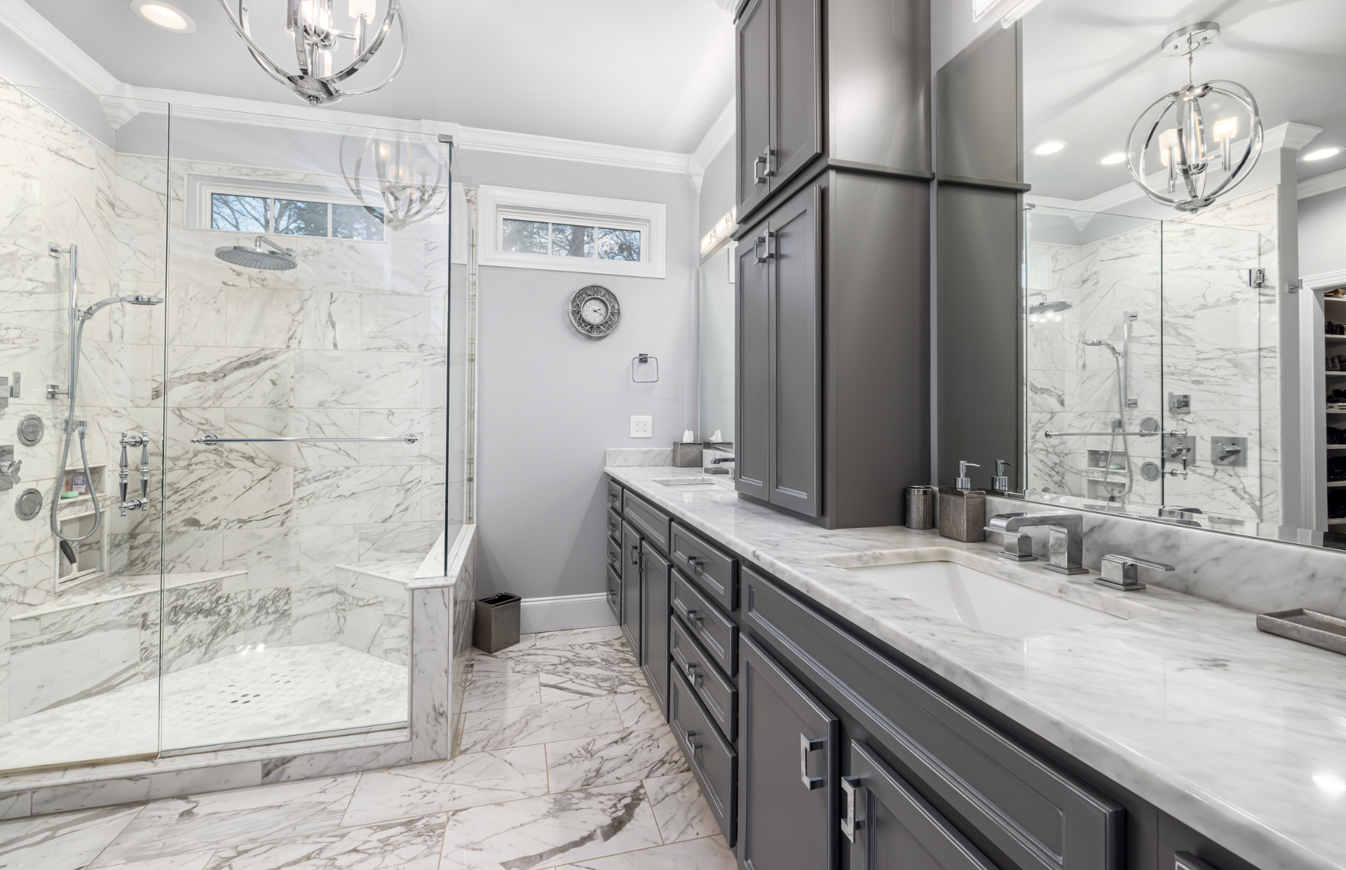 Modern marble bathroom with glass shower, double vanity, and large mirrors
