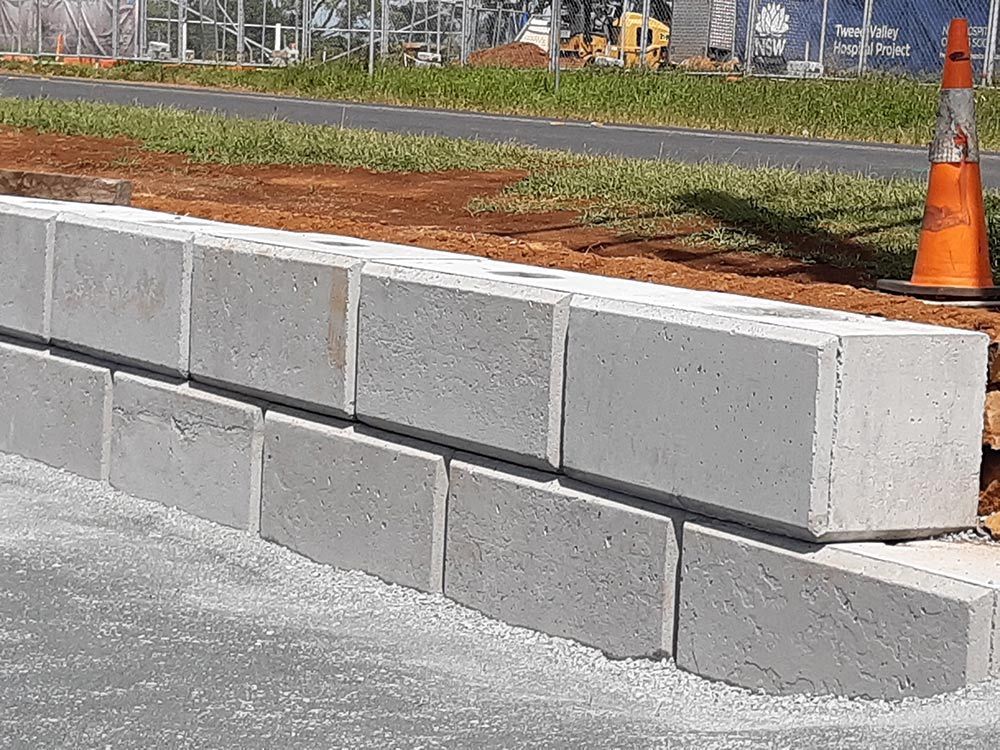 A Concrete Precast Blocks Wall Is Being Built Next To An Orange Traffic Cone — CJR Group Concrete Construction In Gold Coast, QLD